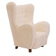 Overpolstret højrygget hvilestol fremstår med nyt betræk i form af lammeuld. Danmark ca. år 1935-40. H: 107cm. B: 81cm