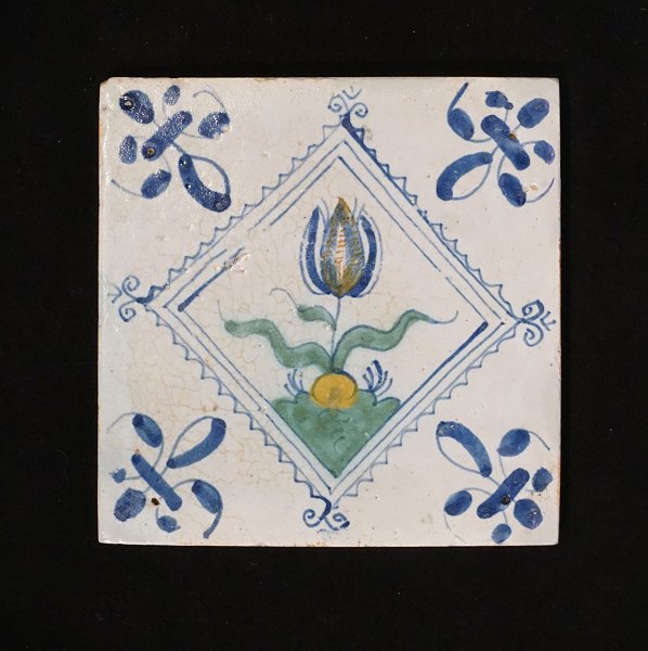 Polykromdekoreret hollandsk flise med tulipanmotiv. Cirka 1620-40. Mål: 13x13cm